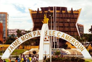 Yaoundé city landmark arch reading “J’aime mon pays le Cameroun,” with the Palais des Congrès building in the background, representing the host city of the 2026 ISBEE World Congress.